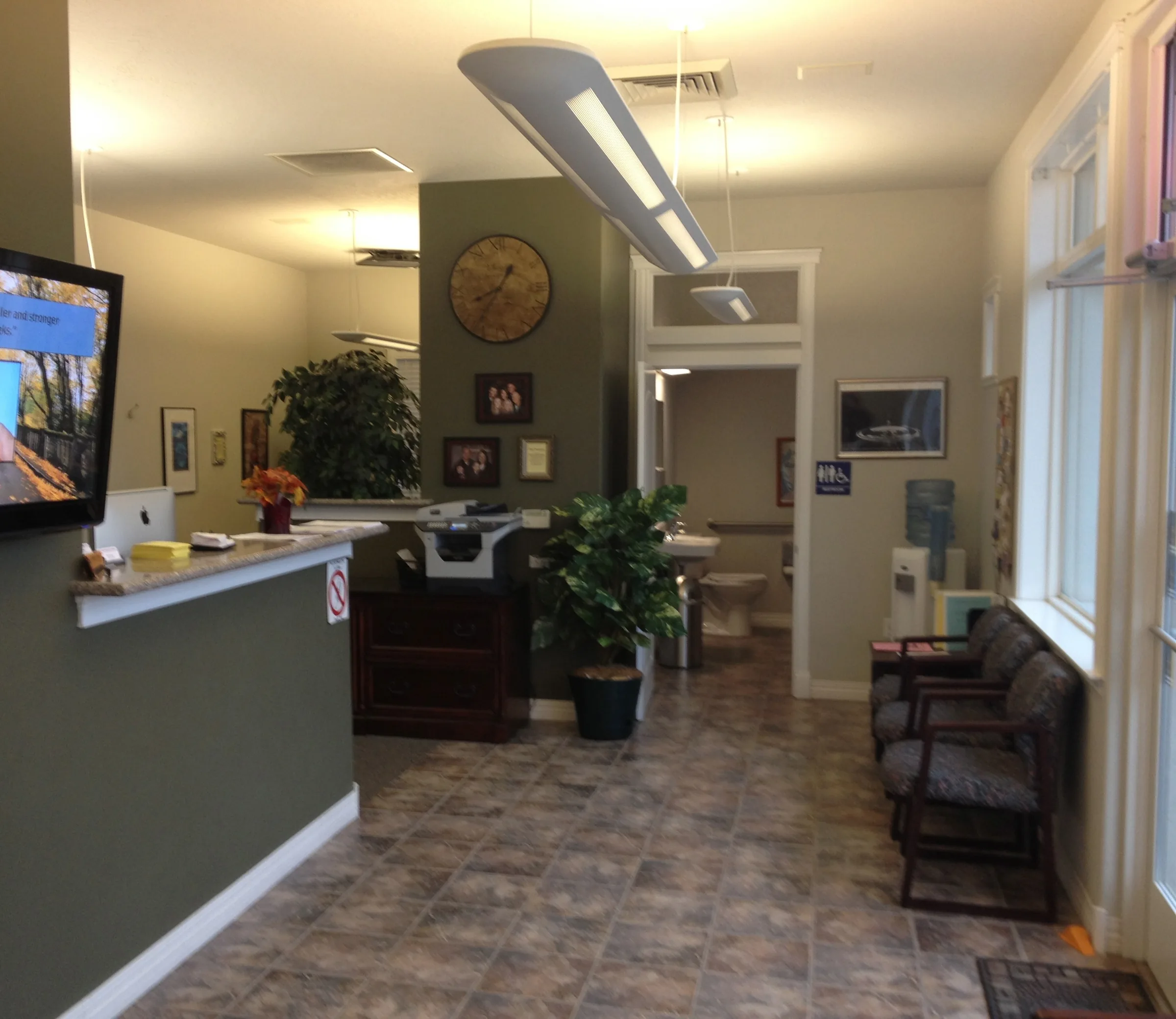 Bright, welcoming reception area of a chiropractic clinic with front desk, seating, and modern lighting.