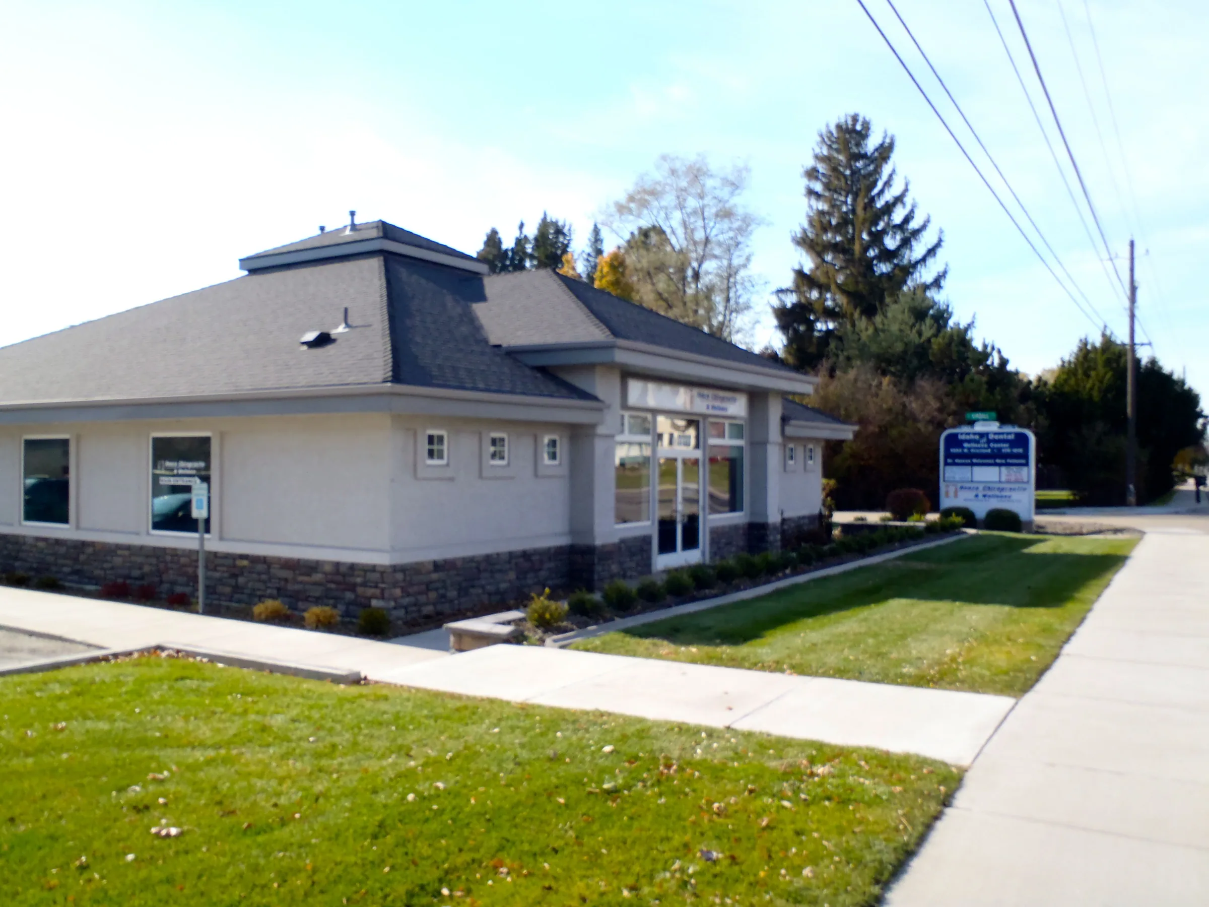 Modern single-story chiropractic clinic building with dark roof and stone base in Boise.